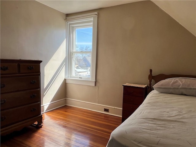 bedroom with vaulted ceiling, baseboards, and hardwood / wood-style floors