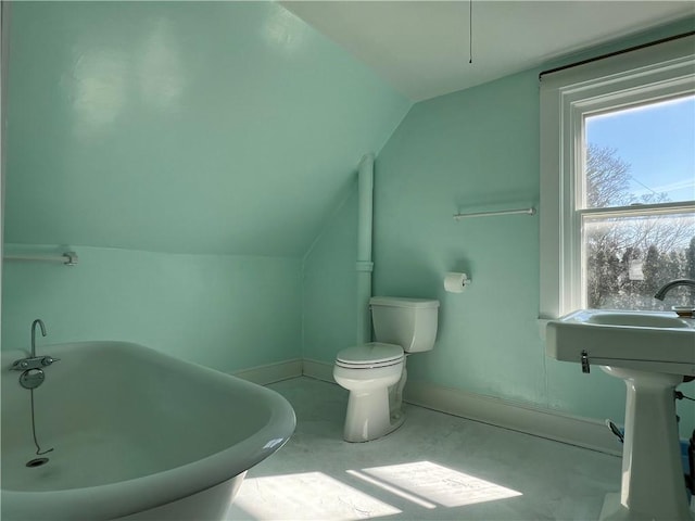 full bathroom with baseboards, toilet, lofted ceiling, and a freestanding tub