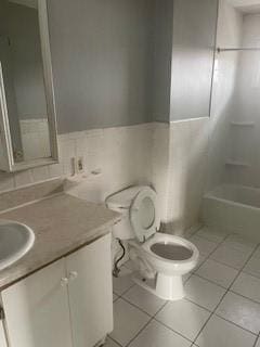 bathroom with tile patterned floors, toilet, tile walls, and vanity