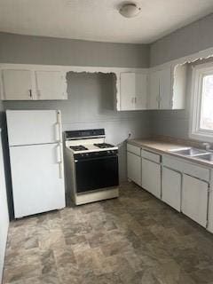 kitchen with a sink, white appliances, and white cabinets