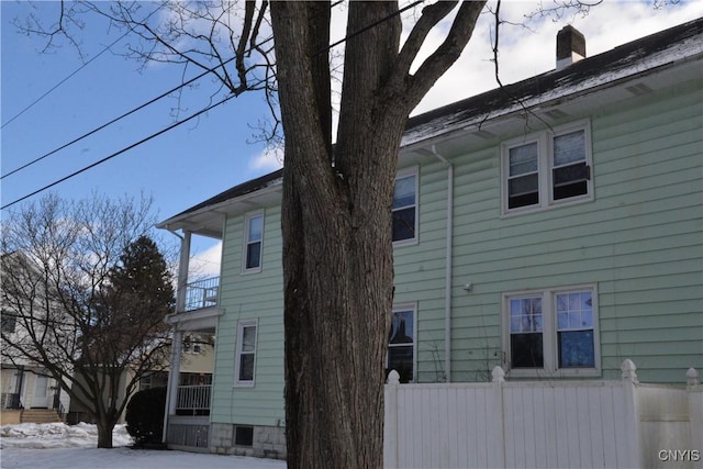 view of home's exterior featuring a chimney and fence