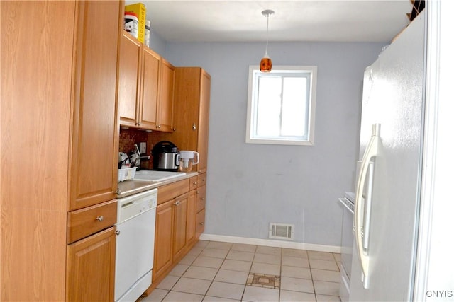 kitchen featuring white appliances, baseboards, visible vents, a sink, and hanging light fixtures