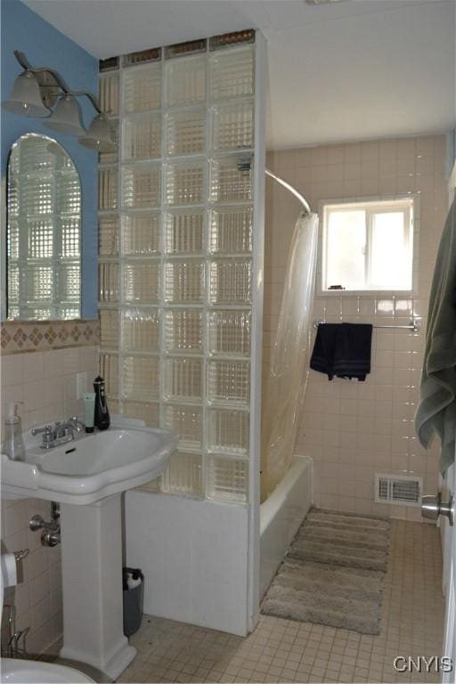 bathroom featuring tile patterned floors, shower / tub combo, tile walls, and visible vents