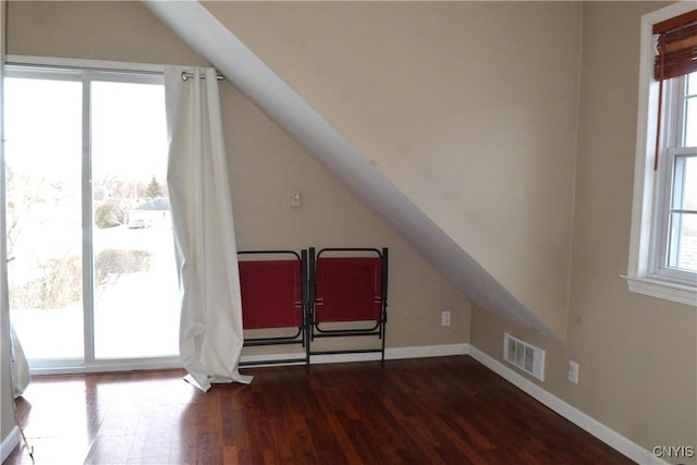 bonus room featuring a wealth of natural light, visible vents, dark wood-style floors, and vaulted ceiling