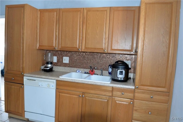 kitchen featuring light countertops, white dishwasher, backsplash, and a sink