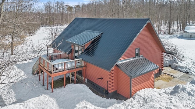 exterior space featuring log siding, a wooden deck, and metal roof