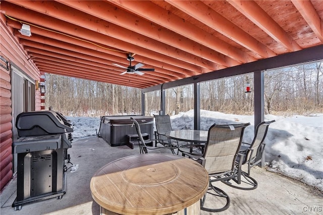 snow covered patio featuring outdoor dining space, a grill, a hot tub, and ceiling fan