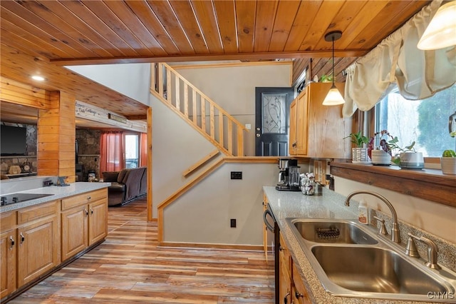 kitchen featuring a sink, wood ceiling, wood walls, pendant lighting, and light wood-type flooring