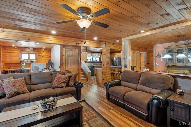 living area with wood finished floors, wood ceiling, wood walls, and ceiling fan