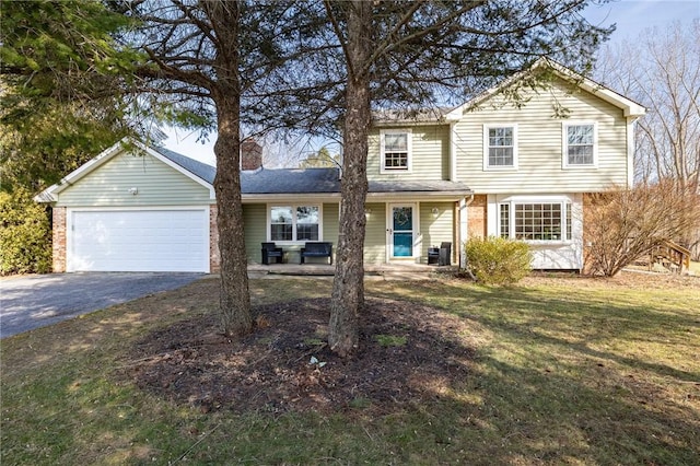 traditional-style house featuring a front yard, driveway, an attached garage, a chimney, and brick siding