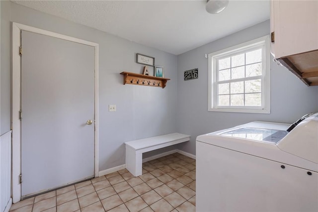 clothes washing area featuring a textured ceiling, cabinet space, separate washer and dryer, light tile patterned floors, and baseboards