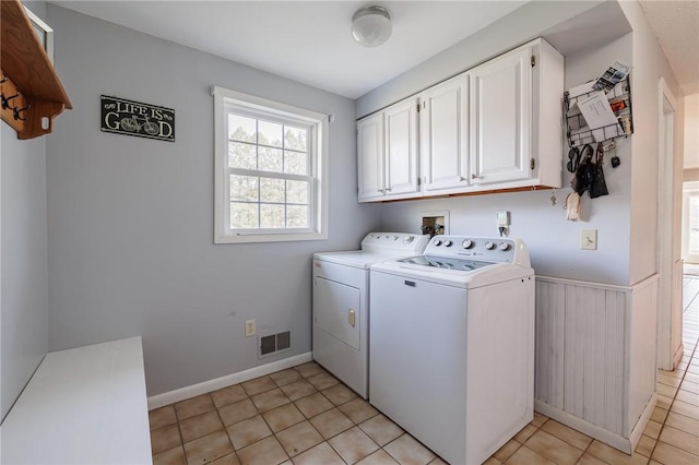 laundry area with visible vents, a wainscoted wall, washer and dryer, cabinet space, and light tile patterned flooring