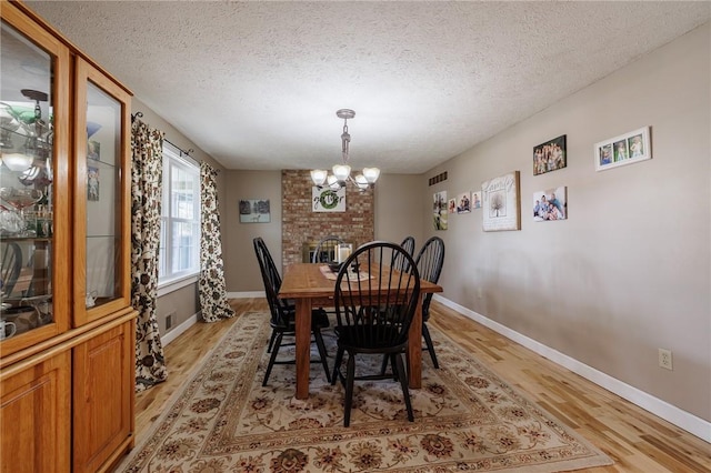 dining space featuring visible vents, a textured ceiling, an inviting chandelier, and light wood-style flooring