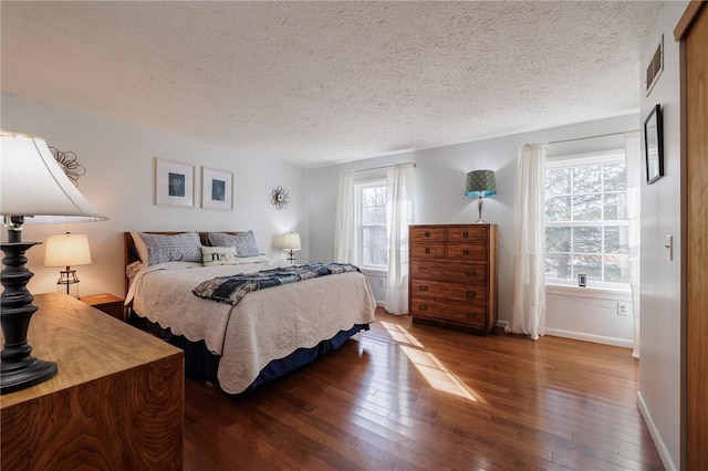 bedroom with hardwood / wood-style flooring, baseboards, and a textured ceiling