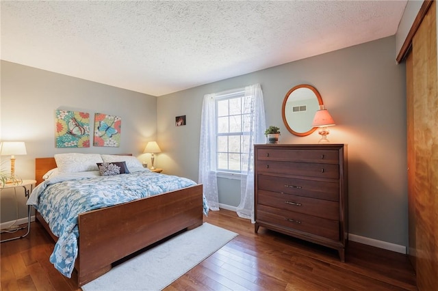 bedroom featuring hardwood / wood-style flooring, baseboards, and a textured ceiling