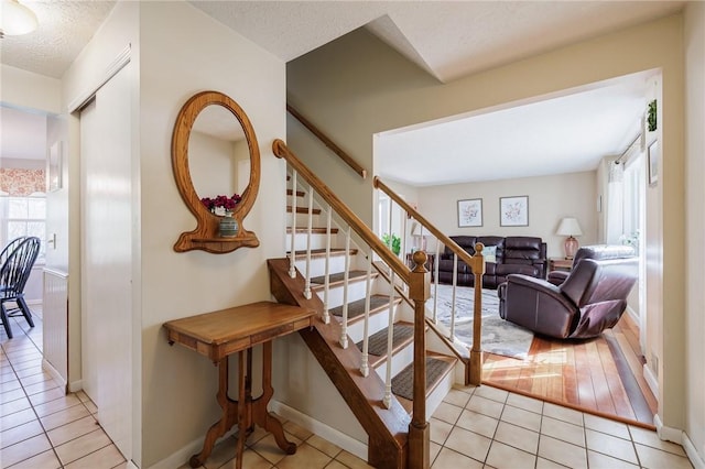 stairs with tile patterned floors, baseboards, and a textured ceiling