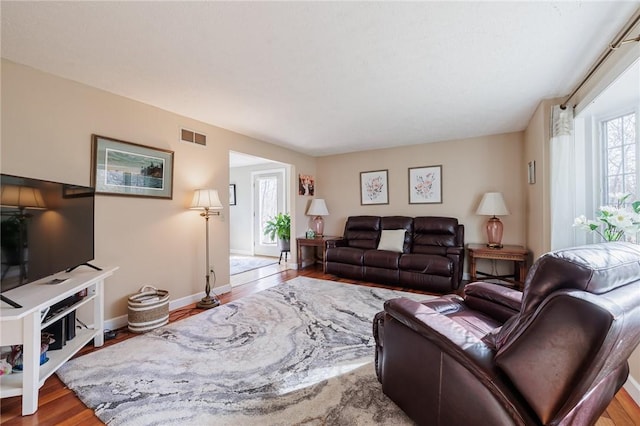 living room with wood finished floors, visible vents, and baseboards