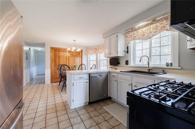 kitchen with a sink, stainless steel appliances, a peninsula, white cabinets, and a chandelier