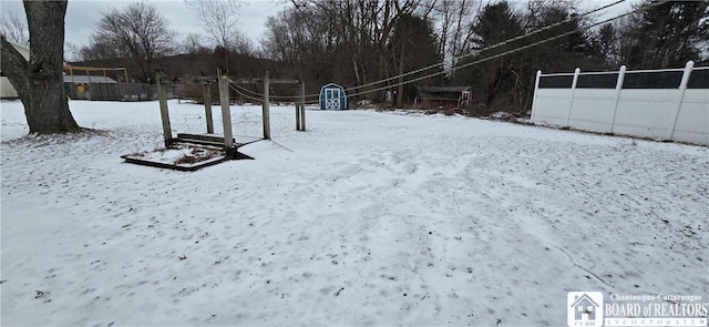 snowy yard featuring fence