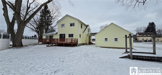 snow covered property with fence and a wooden deck