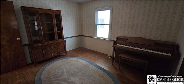 living area with visible vents, wallpapered walls, and wood finished floors