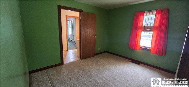 carpeted spare room with a wealth of natural light, visible vents, and baseboards