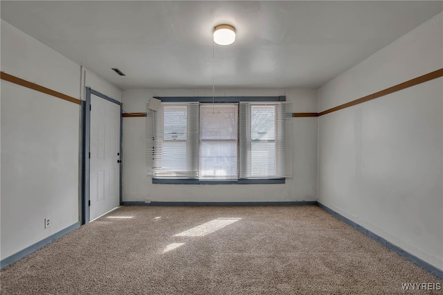 carpeted spare room with visible vents and baseboards