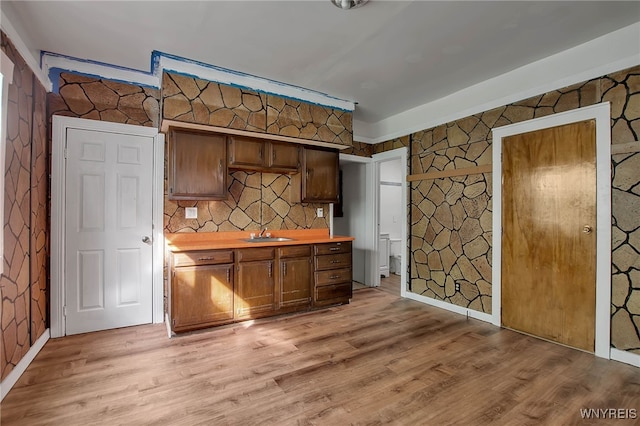 kitchen with a sink, baseboards, and light wood-style floors