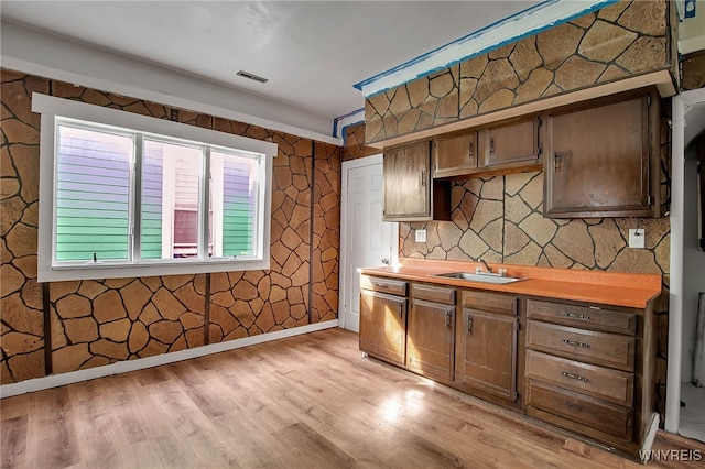 kitchen featuring baseboards, visible vents, a sink, light countertops, and light wood-style floors