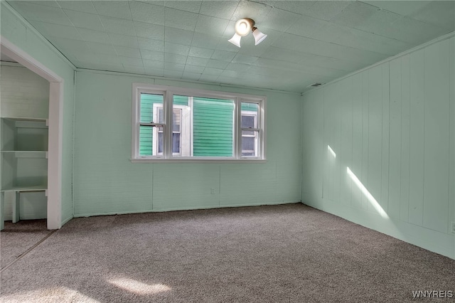 spare room with carpet, visible vents, and brick wall