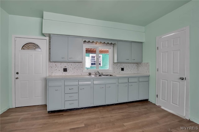 kitchen with light countertops, wood finished floors, tasteful backsplash, and a sink