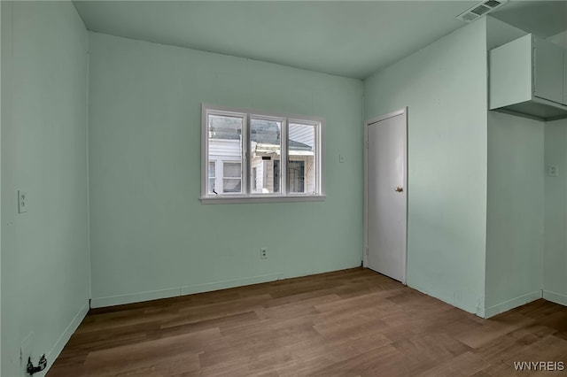 spare room featuring visible vents and wood finished floors