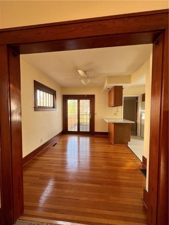 unfurnished living room featuring hardwood / wood-style flooring, visible vents, baseboards, and ceiling fan