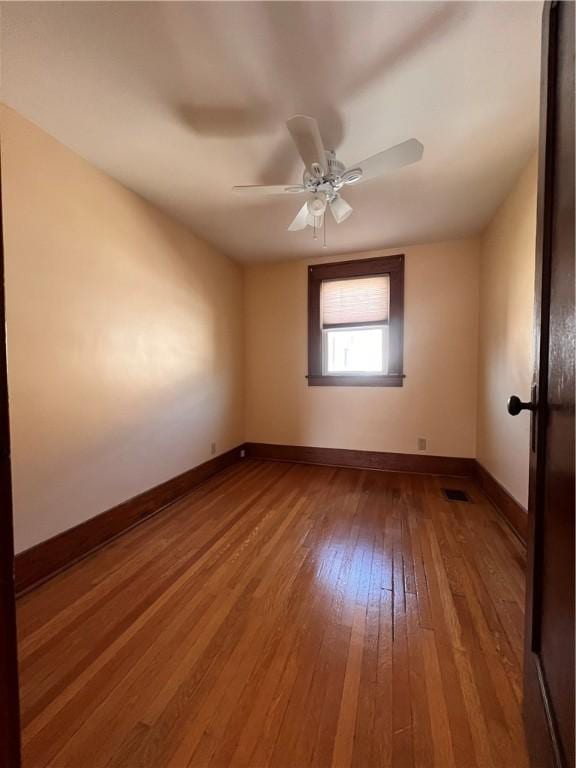 empty room featuring visible vents, ceiling fan, baseboards, and hardwood / wood-style floors