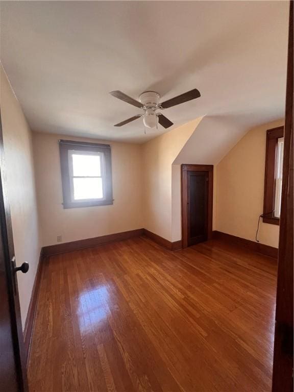 empty room with baseboards, wood finished floors, a ceiling fan, and vaulted ceiling