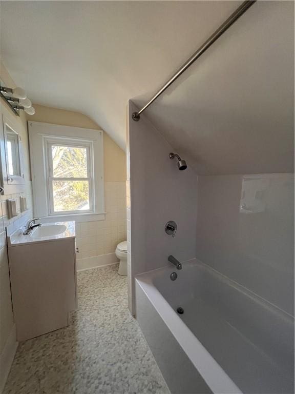 full bathroom featuring vanity, vaulted ceiling, shower / bath combination, tile walls, and toilet