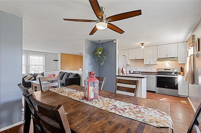 dining space featuring baseboards, a textured ceiling, a ceiling fan, and wood finished floors