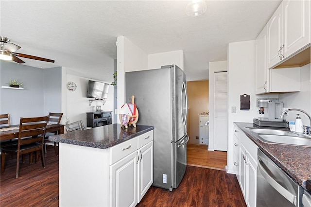 kitchen with dark countertops, ceiling fan, dark wood-style floors, stainless steel appliances, and a sink