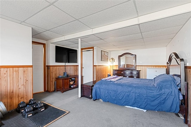 bedroom featuring a wainscoted wall, a paneled ceiling, wood walls, and carpet flooring