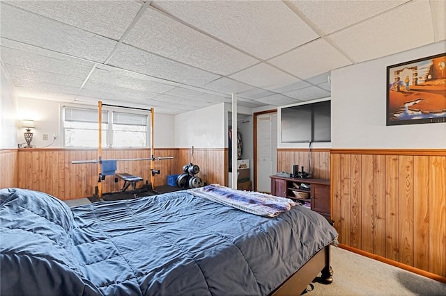 carpeted bedroom featuring a drop ceiling, a wainscoted wall, and wood walls