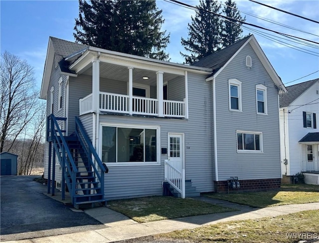 traditional-style house with an outbuilding, a front lawn, entry steps, stairway, and a balcony