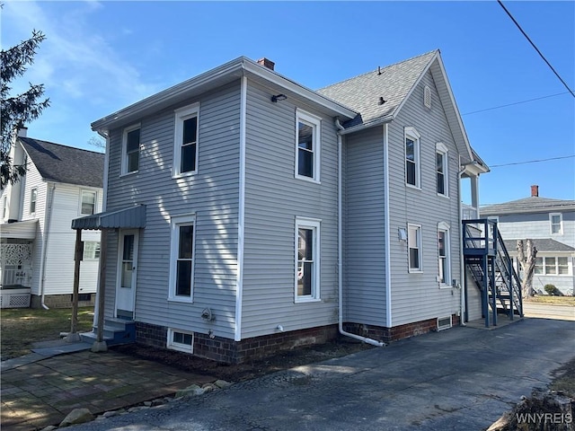 view of side of home with entry steps and a chimney