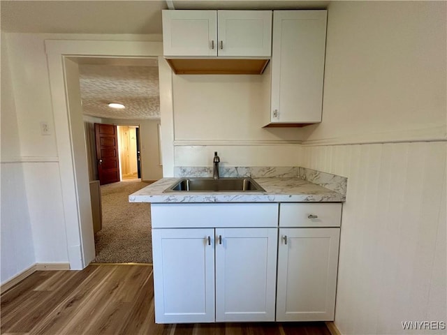 kitchen featuring a sink, wood finished floors, and white cabinets