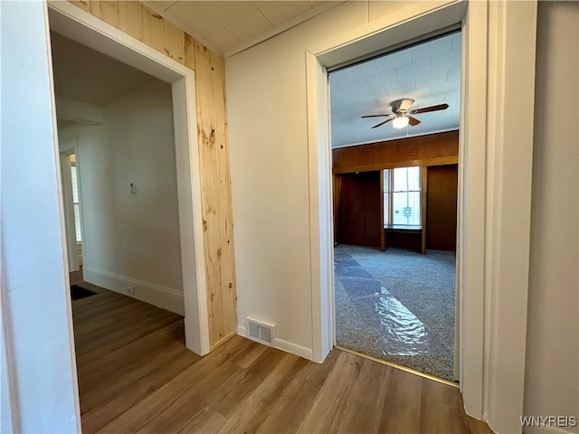 hall with visible vents, baseboards, and wood finished floors