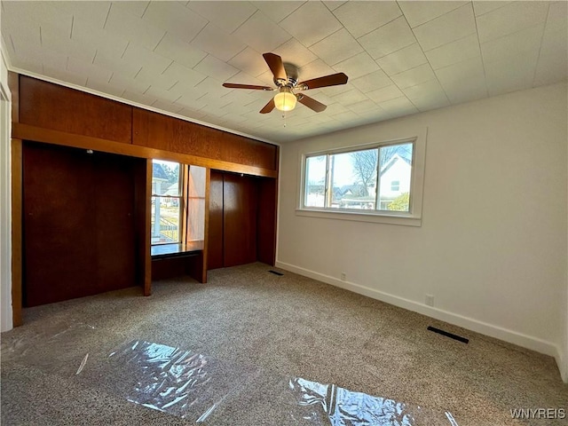 unfurnished bedroom featuring visible vents, baseboards, carpet, and ceiling fan