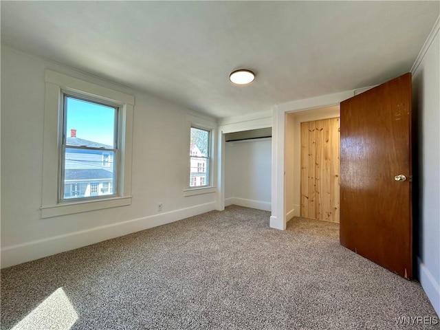 unfurnished bedroom featuring baseboards, a closet, and light carpet