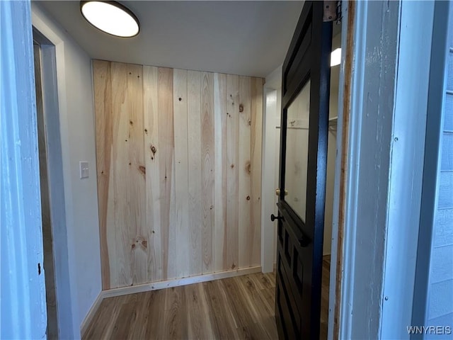 hallway featuring wood finished floors and wood walls