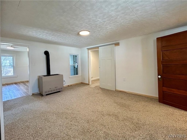 interior space with a wood stove, heating unit, and baseboards