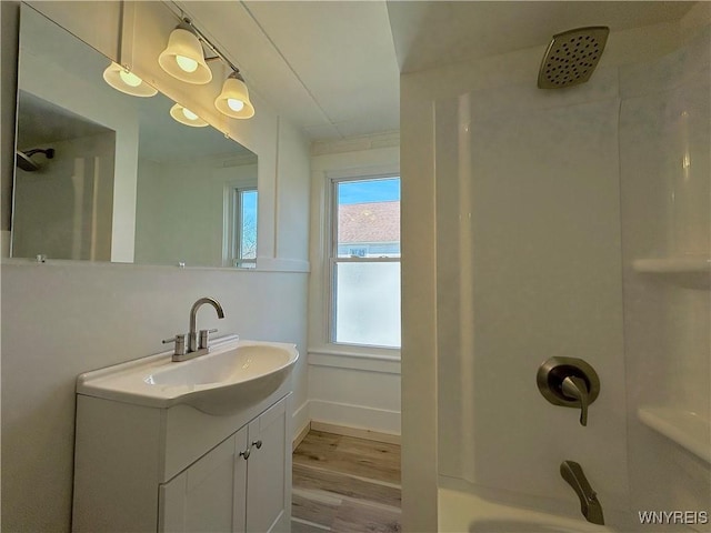 bathroom featuring tub / shower combination, baseboards, wood finished floors, and vanity