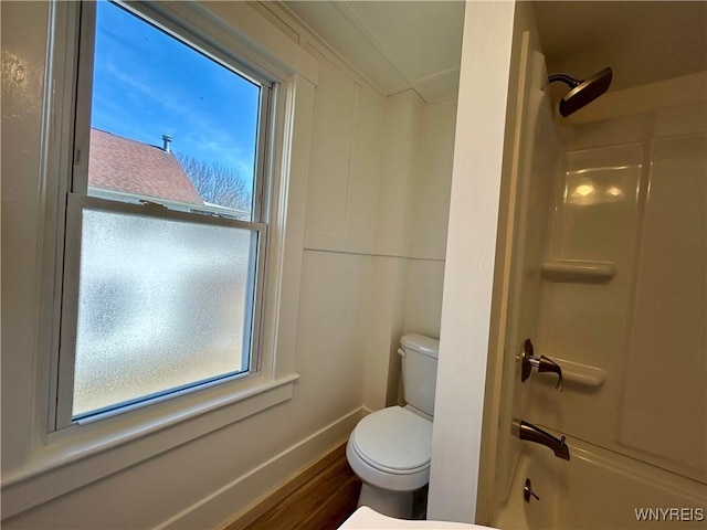 bathroom with baseboards, toilet, wood finished floors, and shower / bathtub combination